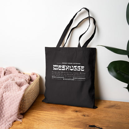 Black Meshugge definition tote lying against a wall