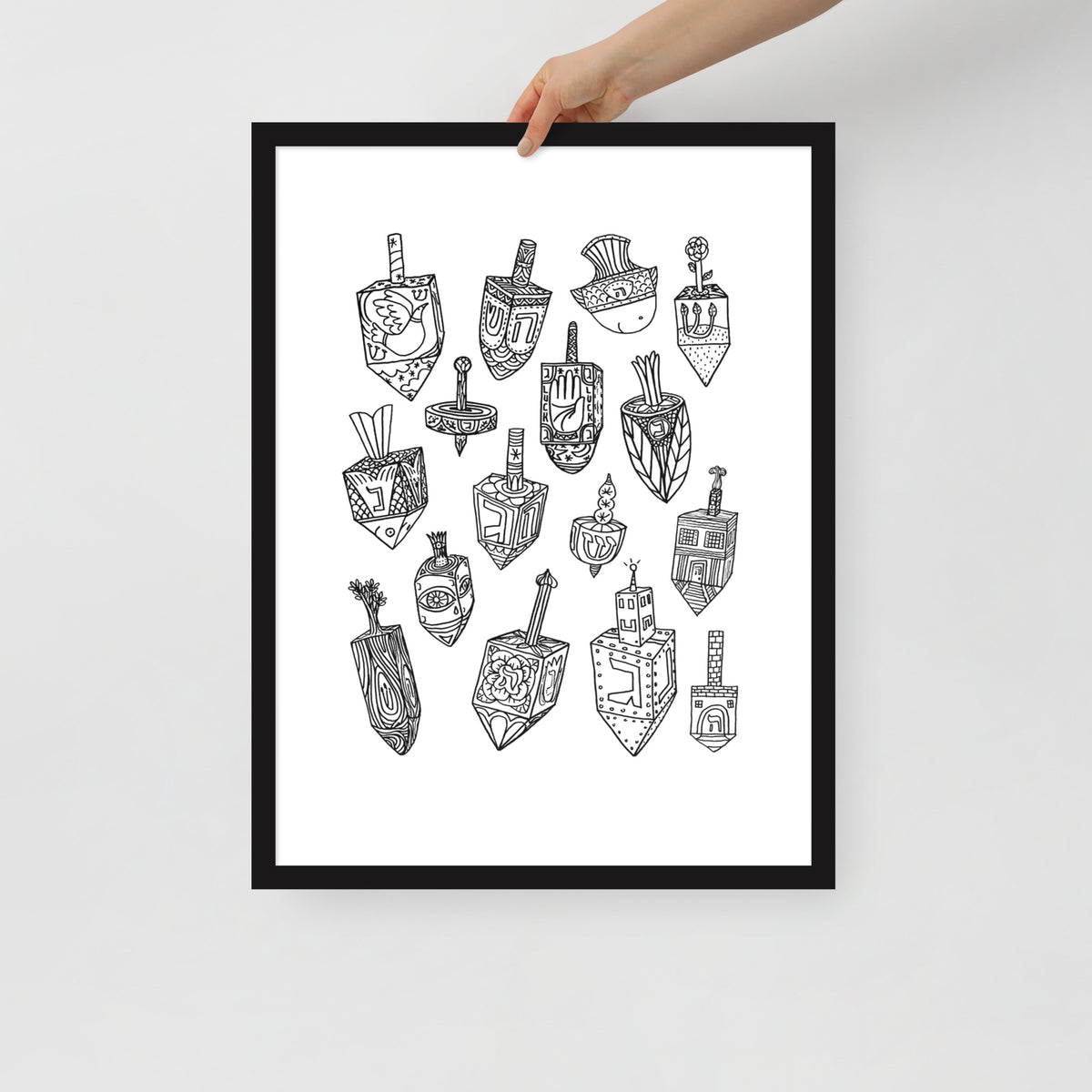 A hand holding the Meshugge dreidel poster to show the scale of the frame