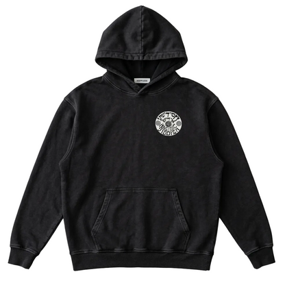 A black washed pullover hoodie with a circular white graphic on the left chest, laid flat on a light gray fabric background.