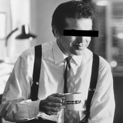 Man holding white Meshugge mug 