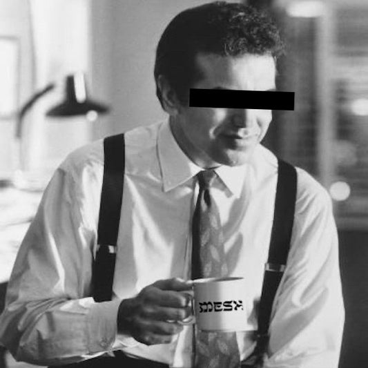 Man holding white Meshugge mug 