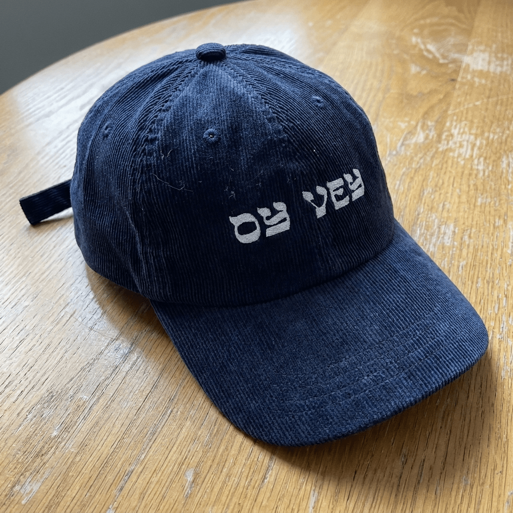 Oy Vey corduroy cap on wooden table
