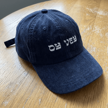 Oy Vey corduroy cap on wooden table