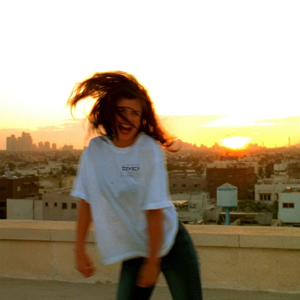 Woman wearing Mensch heart Tshirt in white on a rooftop in Israel