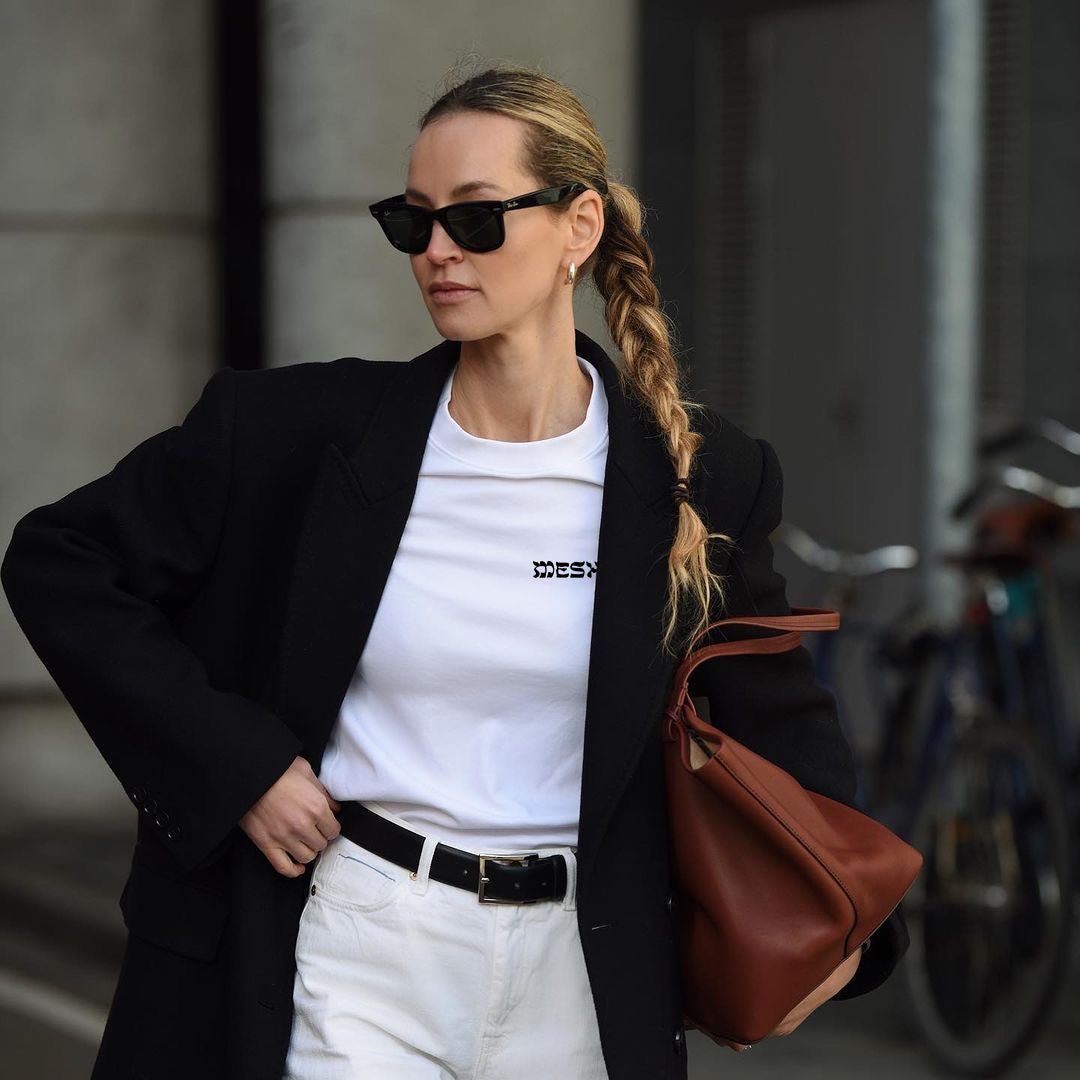 Woman wearing a black trench coat and white Meshugge T-shirt