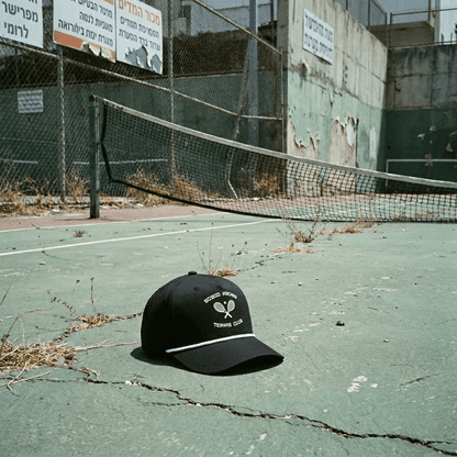 'Goyim Naches' Tennis Club Cap Black laying on tennis court