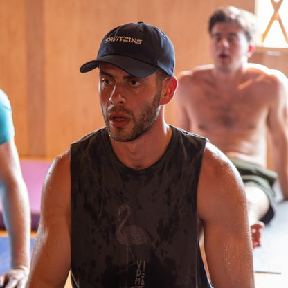 man wearing a Shvitzing hat, sweating at a yoga class