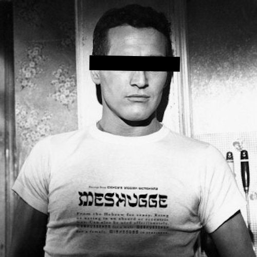Black and white photo of a man wearing a white graphic t-shirt with the word 'MESHUGUE' in a stylized font, with his face obscured by a black bar.